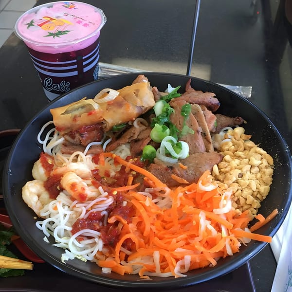 BMC Pho's vermicelli bowl with shrimp, pork, egg roll, peanuts, and shredded carrots, with a pink drink.