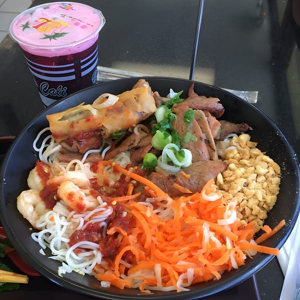 BMC Pho vermicelli bowl with shrimp, pork, egg roll, peanuts, and shredded carrots, with a pink drink.
